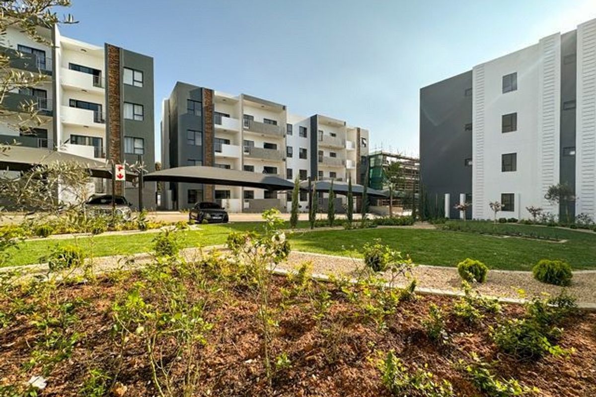 A well-maintained residential complex featuring modern multi-story apartment blocks, landscaped gardens, and covered parking areas.
