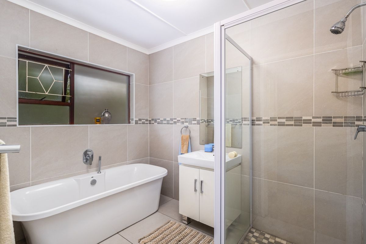 A modern bathroom featuring a freestanding bathtub, a separate glass-enclosed shower, and a vanity unit with neutral wall tiling.
