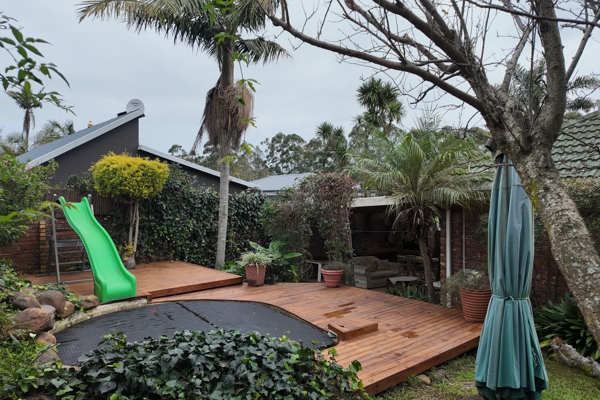 A private rear garden featuring a timber deck, established landscaping, and a covered patio area, providing a functional outdoor space for relaxation.