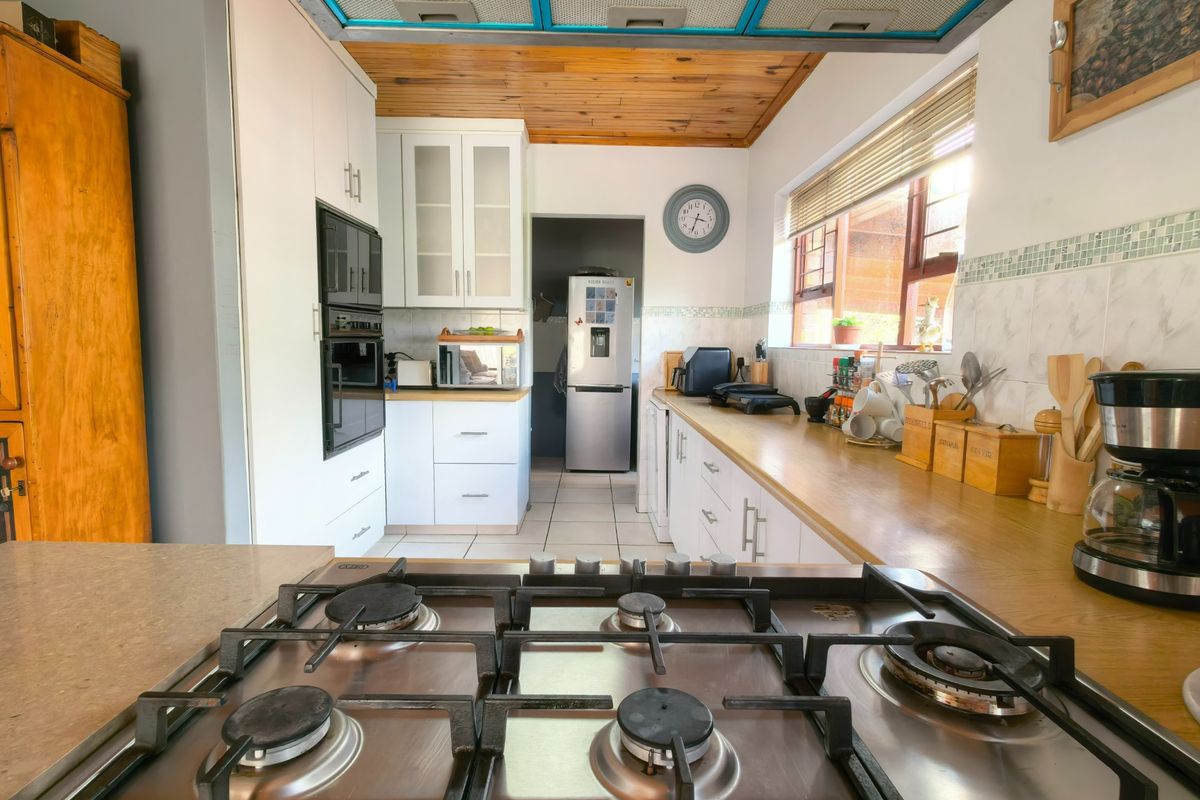 A functional kitchen featuring a gas hob, built-in oven, wooden countertops, and a distinctive timber ceiling with an integrated extractor fan.