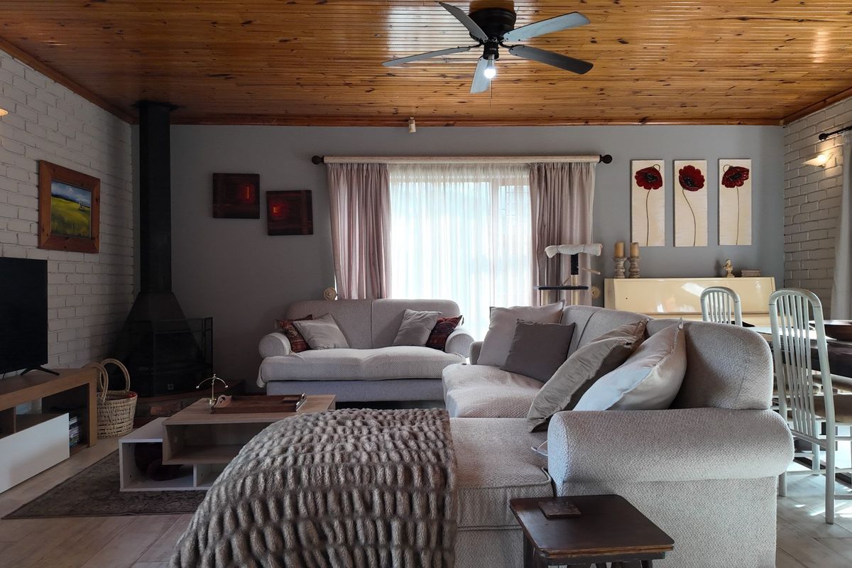 A cozy living room featuring a wood-paneled ceiling, a freestanding fireplace, and a painted brick wall, creating a warm and inviting atmosphere.