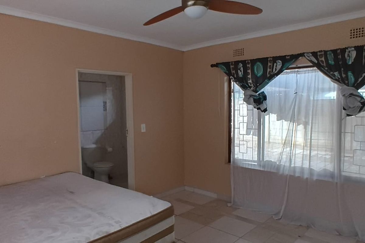 A bedroom featuring tiled flooring, a ceiling fan, and an en-suite bathroom access point.