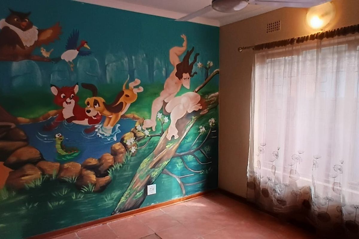 A bedroom featuring a large hand-painted mural on the feature wall, tiled flooring, and a window with curtain rod and ceiling fan.