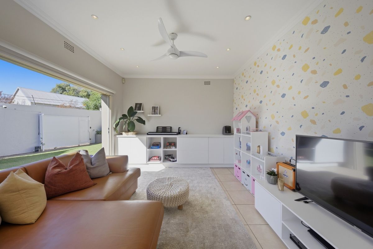 Bright living room featuring built-in cabinetry, recessed ceiling lighting, a ceiling fan, and large sliding glass doors opening to the rear garden.