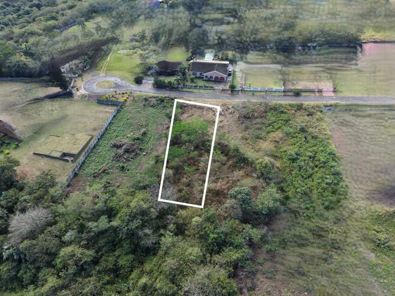 An aerial view of a vacant residential plot of land, highlighting the property boundaries and surrounding natural vegetation.
