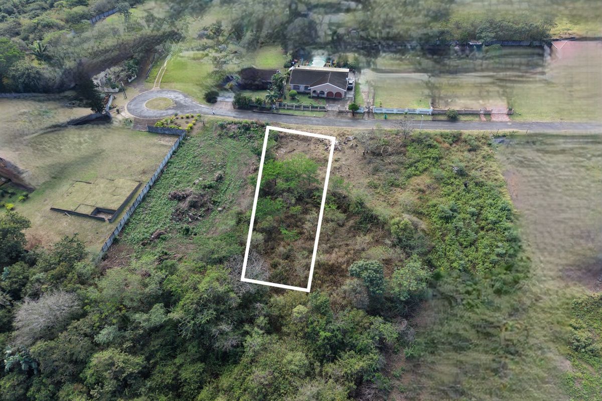An aerial view of a vacant residential plot of land, highlighting the property boundaries and surrounding natural vegetation.