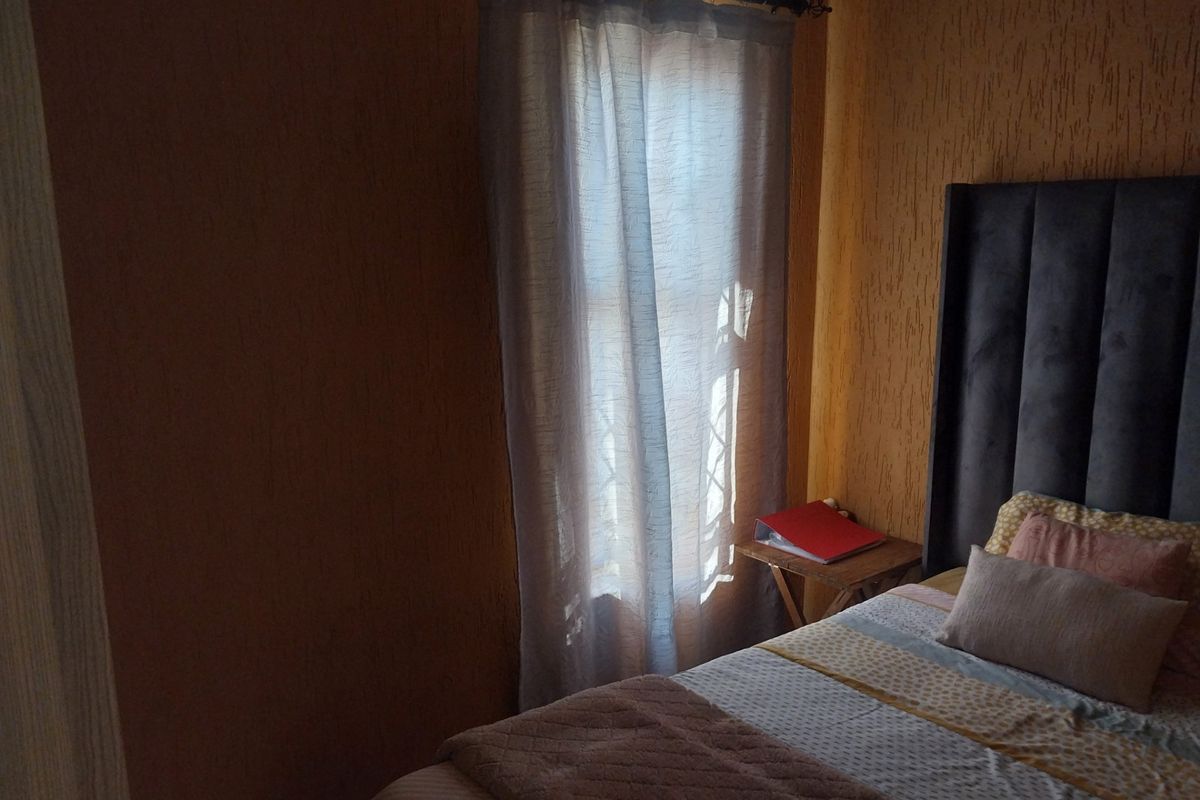 A bedroom featuring textured wall finishes and a window with curtain treatments.