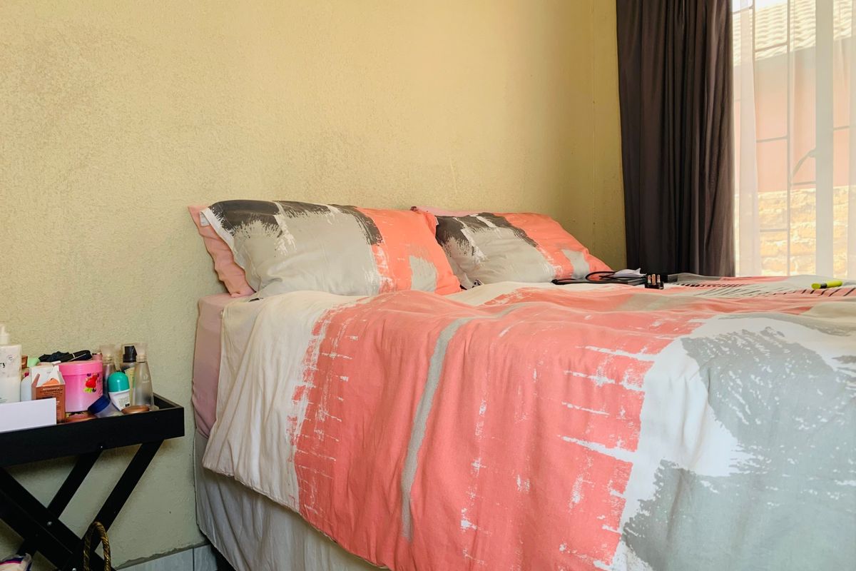 A bedroom featuring tiled flooring and a window with curtain tracks.
