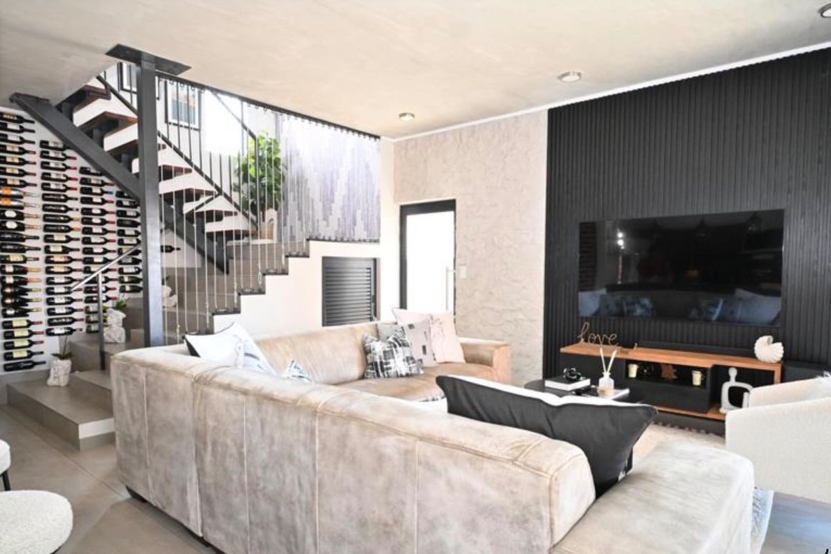 Modern living room featuring a striking open staircase with integrated wine storage and a textured black feature wall.
