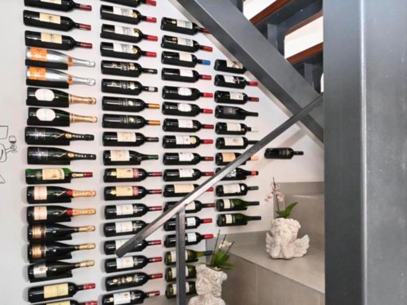 A dedicated wine storage area integrated into the space beneath a modern staircase, featuring wall-mounted wine racks.