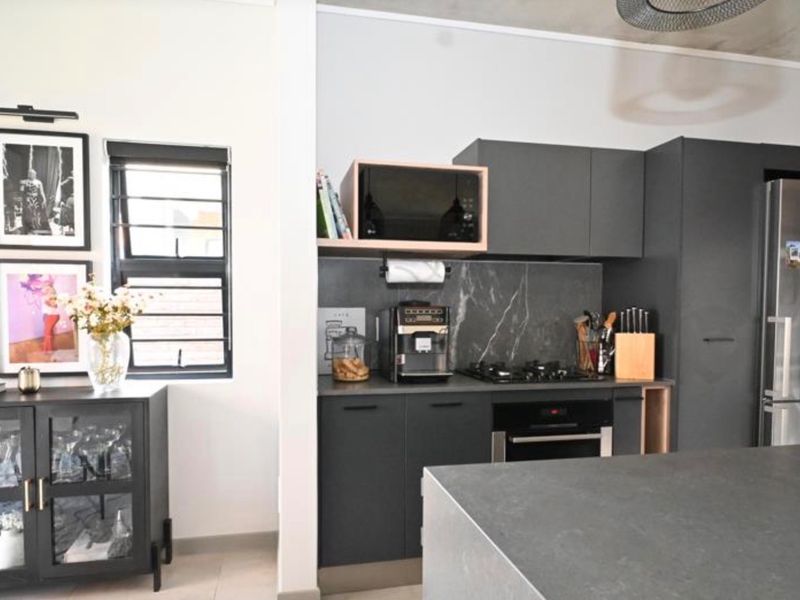 Modern kitchen featuring dark cabinetry, stone countertops, integrated appliances, and a central island, creating a sleek and functional culinary space.