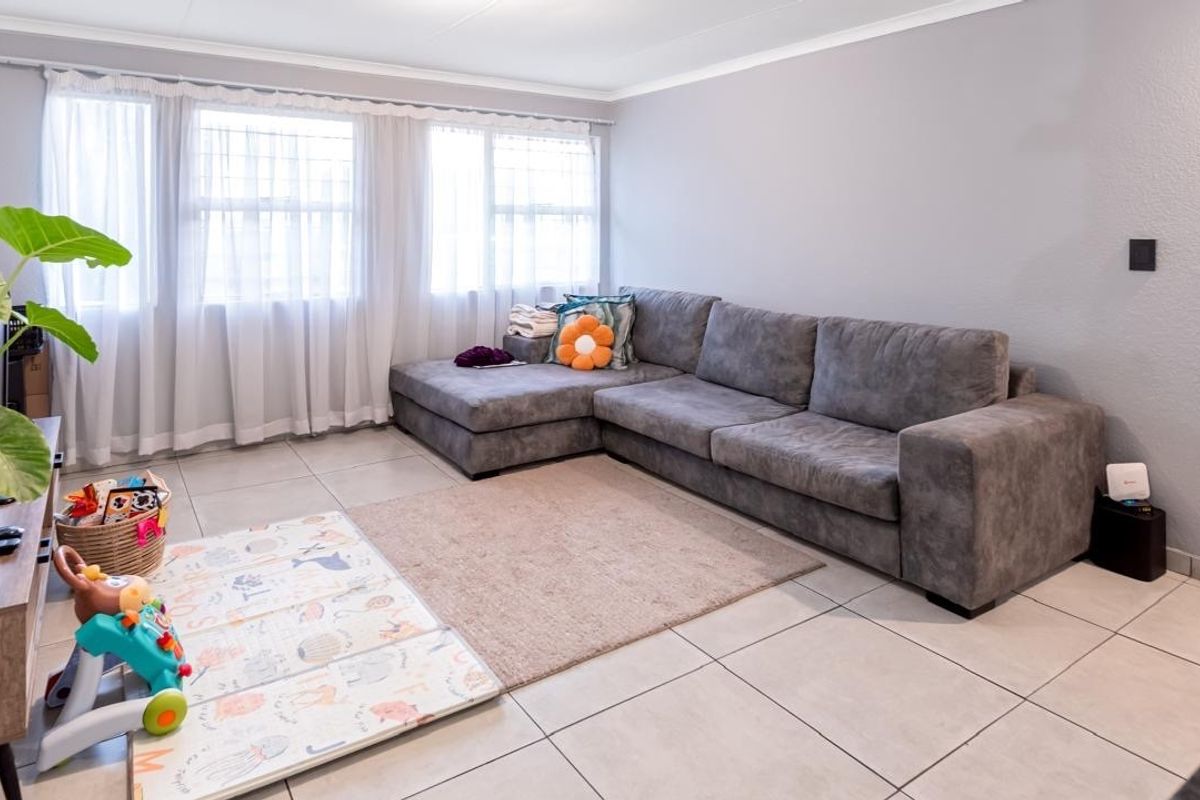 A well-lit living room featuring neutral tiled flooring and clean wall finishes, providing a comfortable and functional space for relaxation.