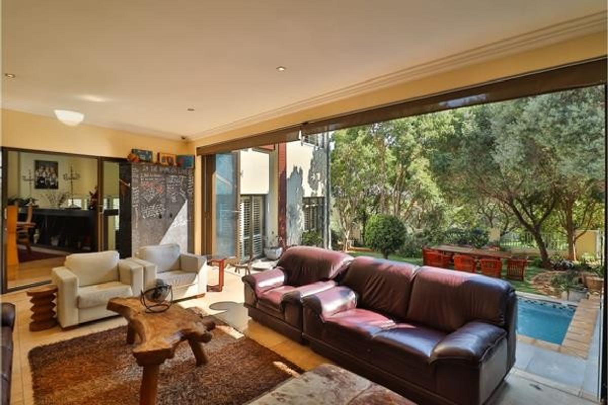 Spacious living room featuring large sliding glass doors that open to a pool area, recessed lighting, and a unique built-in chalkboard wall.