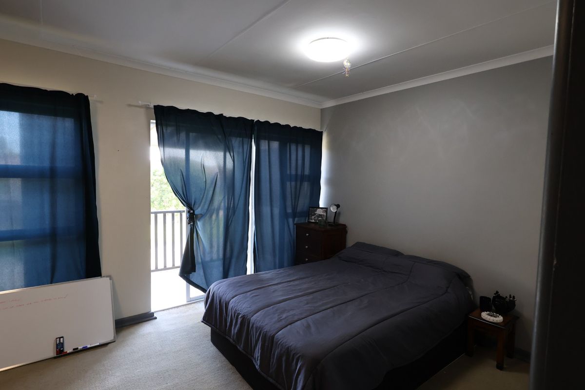 A bedroom featuring carpeted flooring, a ceiling-mounted light fixture, and a sliding glass door providing access to a balcony.