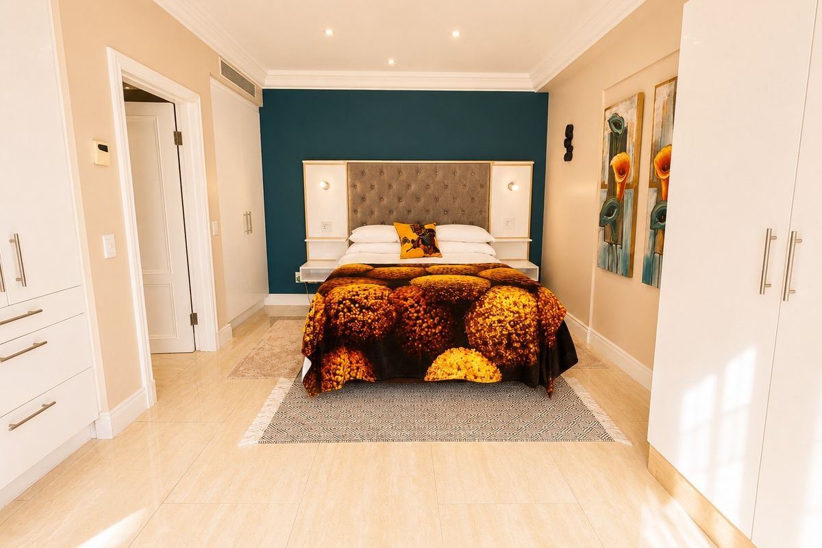 A well-maintained bedroom featuring built-in cupboards, recessed ceiling lighting, and a feature wall with an integrated headboard and bedside lighting.