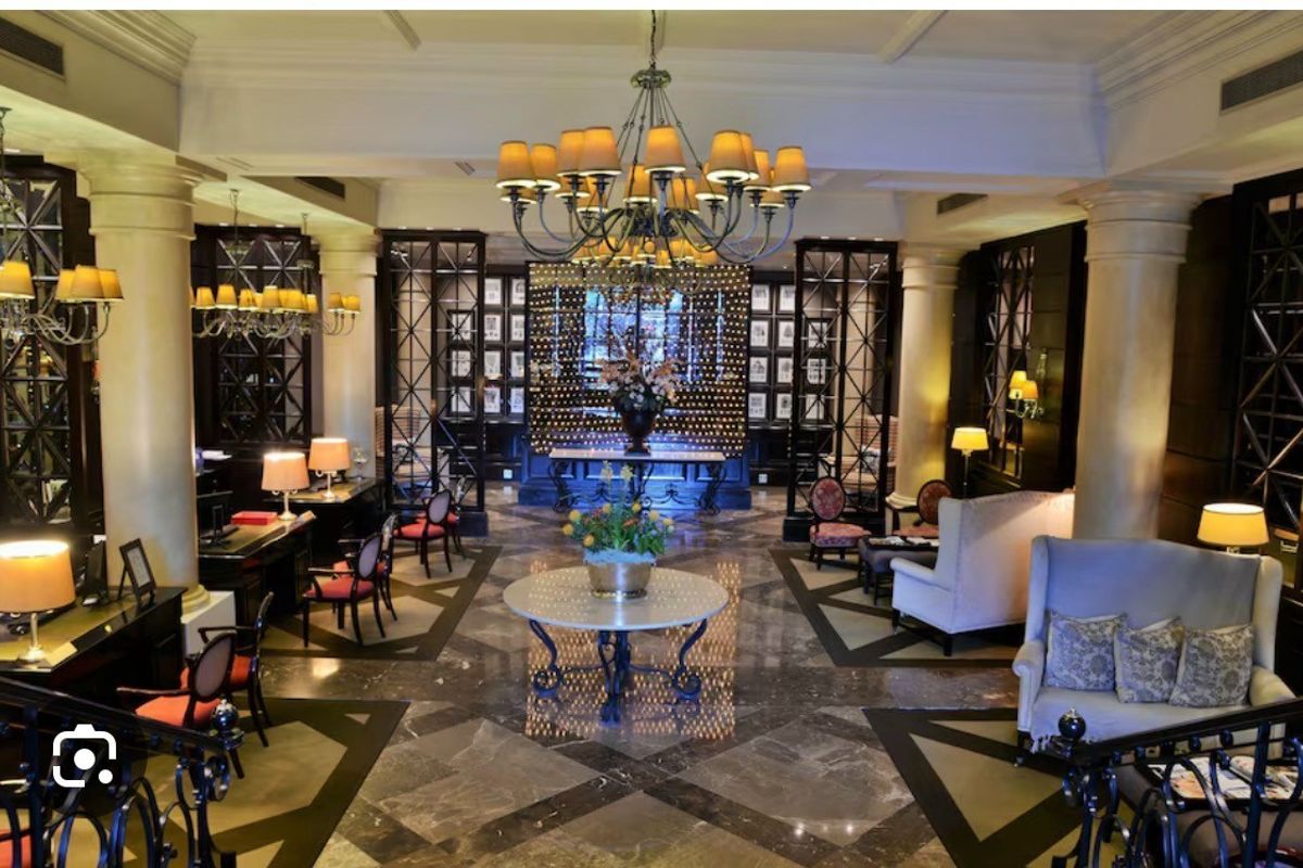Elegant lobby or living area featuring polished marble flooring, decorative columns, intricate metal room dividers, and grand chandeliers.
