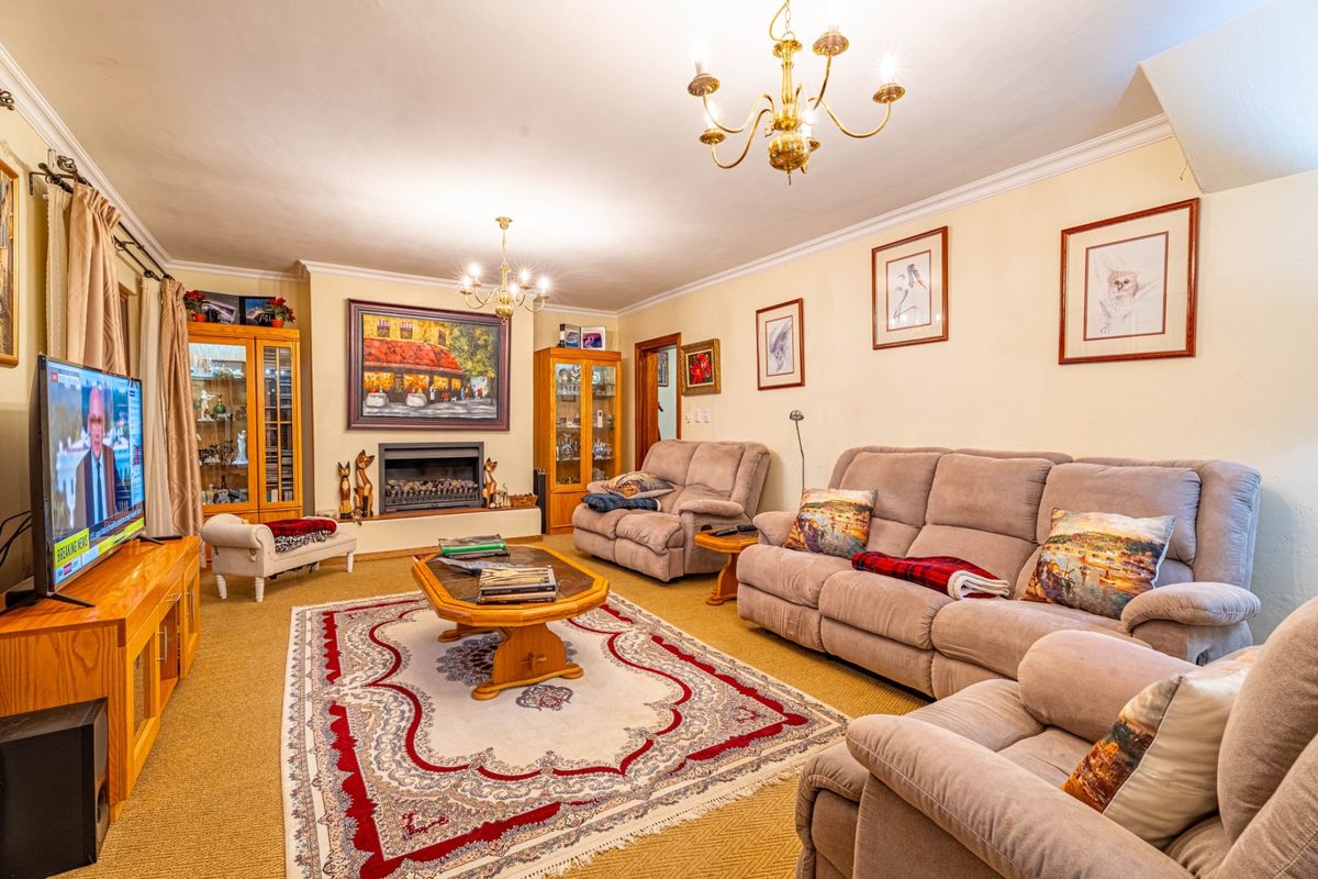 A traditional living room featuring a built-in fireplace, decorative coving, and classic brass chandeliers, offering a warm and comfortable space for relaxation.