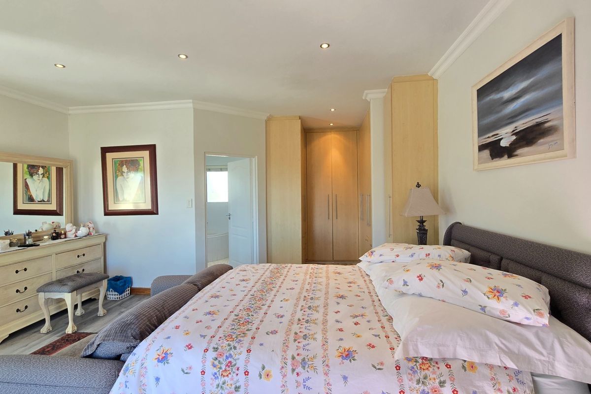 Spacious bedroom featuring built-in light wood cabinetry, recessed ceiling lighting, and an en-suite bathroom access.
