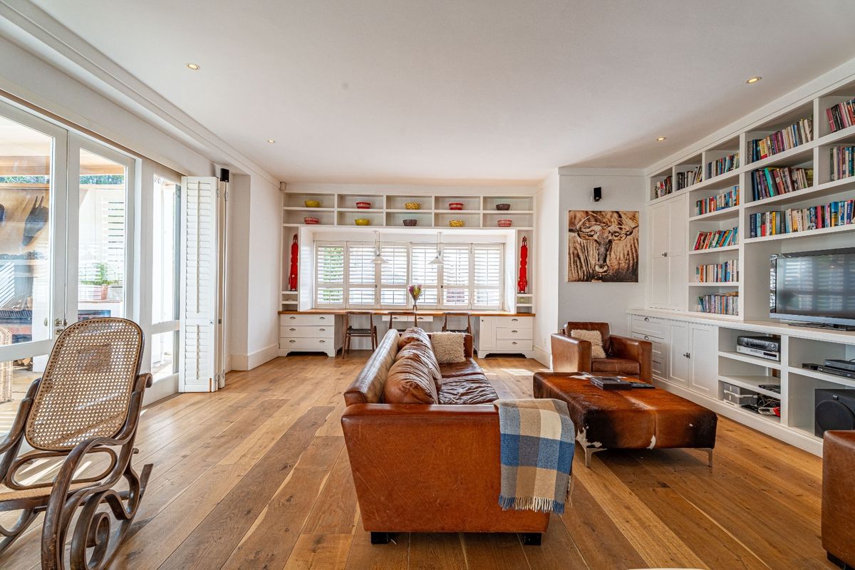 Spacious living room featuring extensive built-in cabinetry, integrated shelving, hardwood flooring, and large glass doors providing ample natural light.