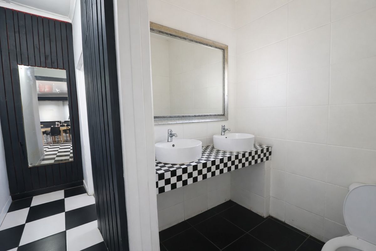 Commercial restroom featuring a double vanity with vessel sinks, checkerboard tiling, and a large wall-mounted mirror.
