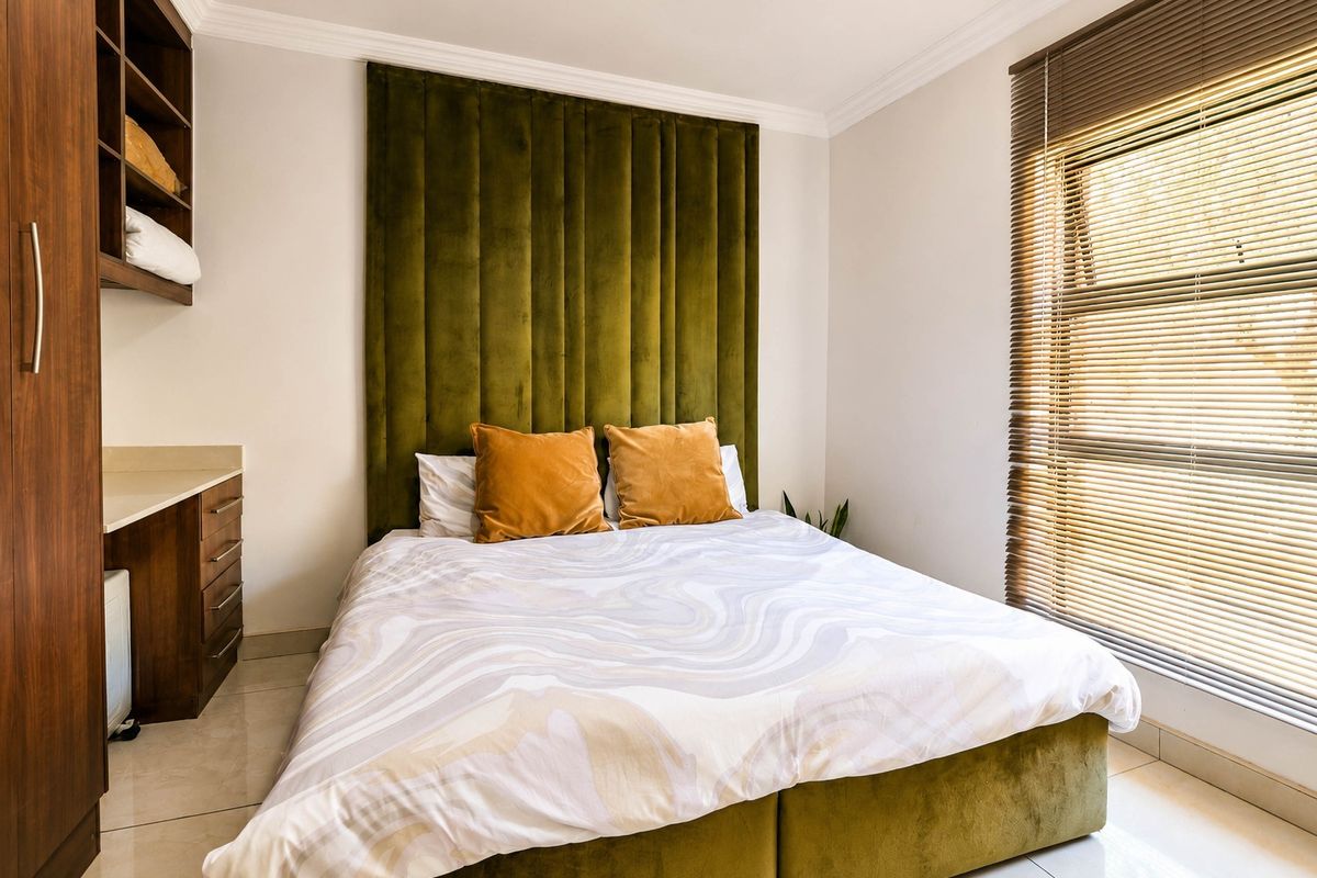 A well-maintained bedroom featuring built-in cabinetry, tiled flooring, crown molding, and large windows with fitted venetian blinds.