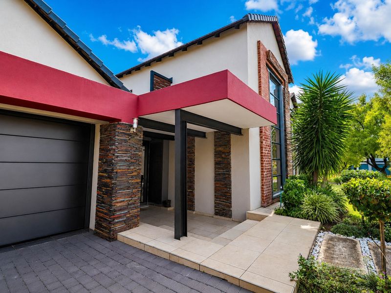 Modern front facade featuring stone cladding, a covered entrance porch, and a paved driveway leading to a sectional garage door.