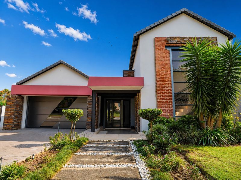 Modern front elevation featuring a combination of brick and stone cladding, a double garage, and a well-maintained landscaped garden with a paved walkway.