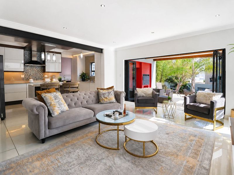 Spacious open-plan living area featuring modern kitchen with island, tiled floors, and seamless indoor-outdoor flow through large bi-fold doors to the patio.