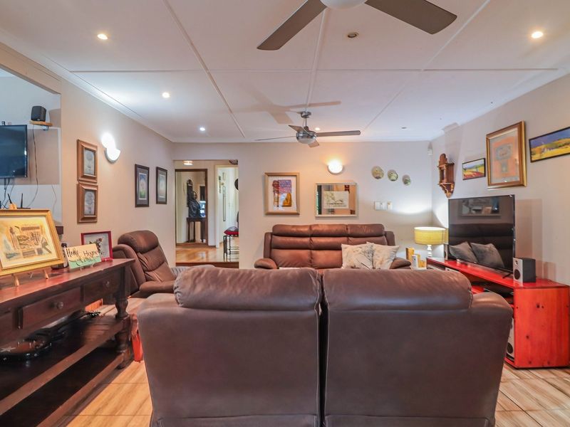 A comfortable living room featuring tiled flooring, recessed downlighting, and dual ceiling fans, providing a functional and well-lit space for relaxation.