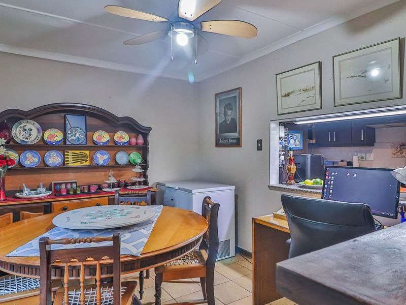 Dining area featuring a ceiling fan and a service window opening into the kitchen, creating a functional connection between the two spaces.