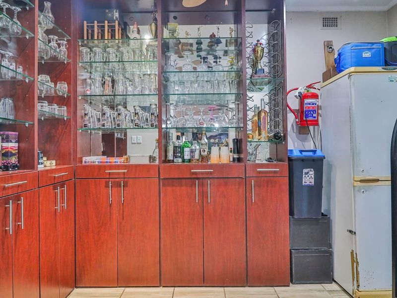 A dedicated bar area featuring extensive built-in wooden cabinetry with integrated glass shelving and display storage.