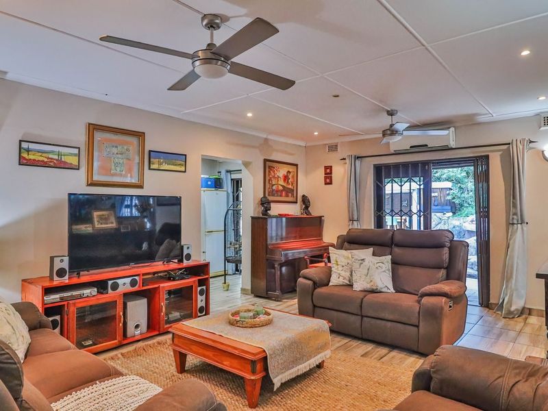 A comfortable living room featuring tiled flooring, ceiling fans, and sliding glass doors that provide direct access to the outdoor area.