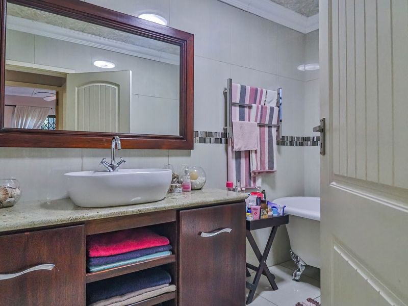 A well-maintained bathroom featuring a vanity with a vessel sink, a large framed mirror, and a classic clawfoot bathtub.