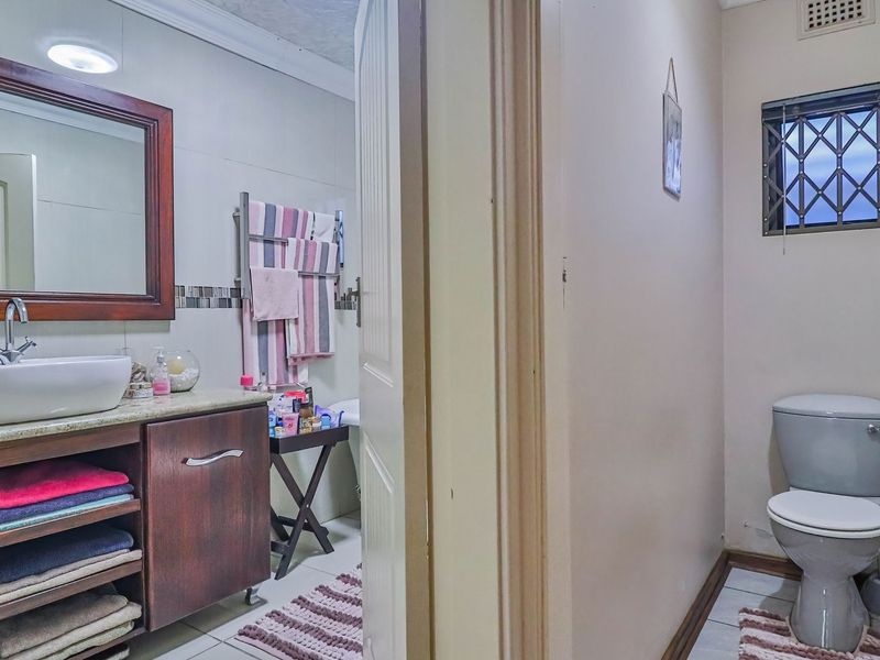 A functional bathroom featuring a vanity with a vessel sink, a separate toilet area, and tiled flooring.