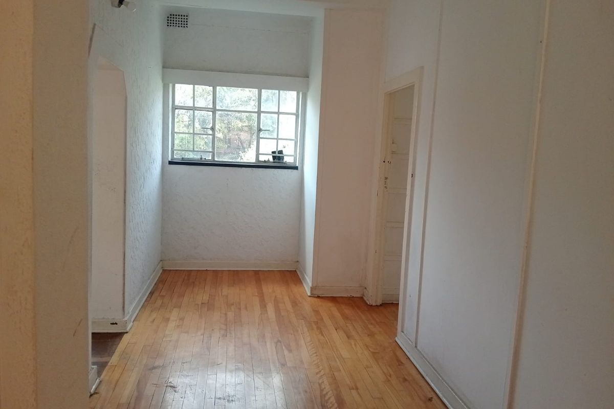 An empty, sunlit room featuring polished timber flooring and neutral walls, offering a versatile space suitable for a bedroom or home office.