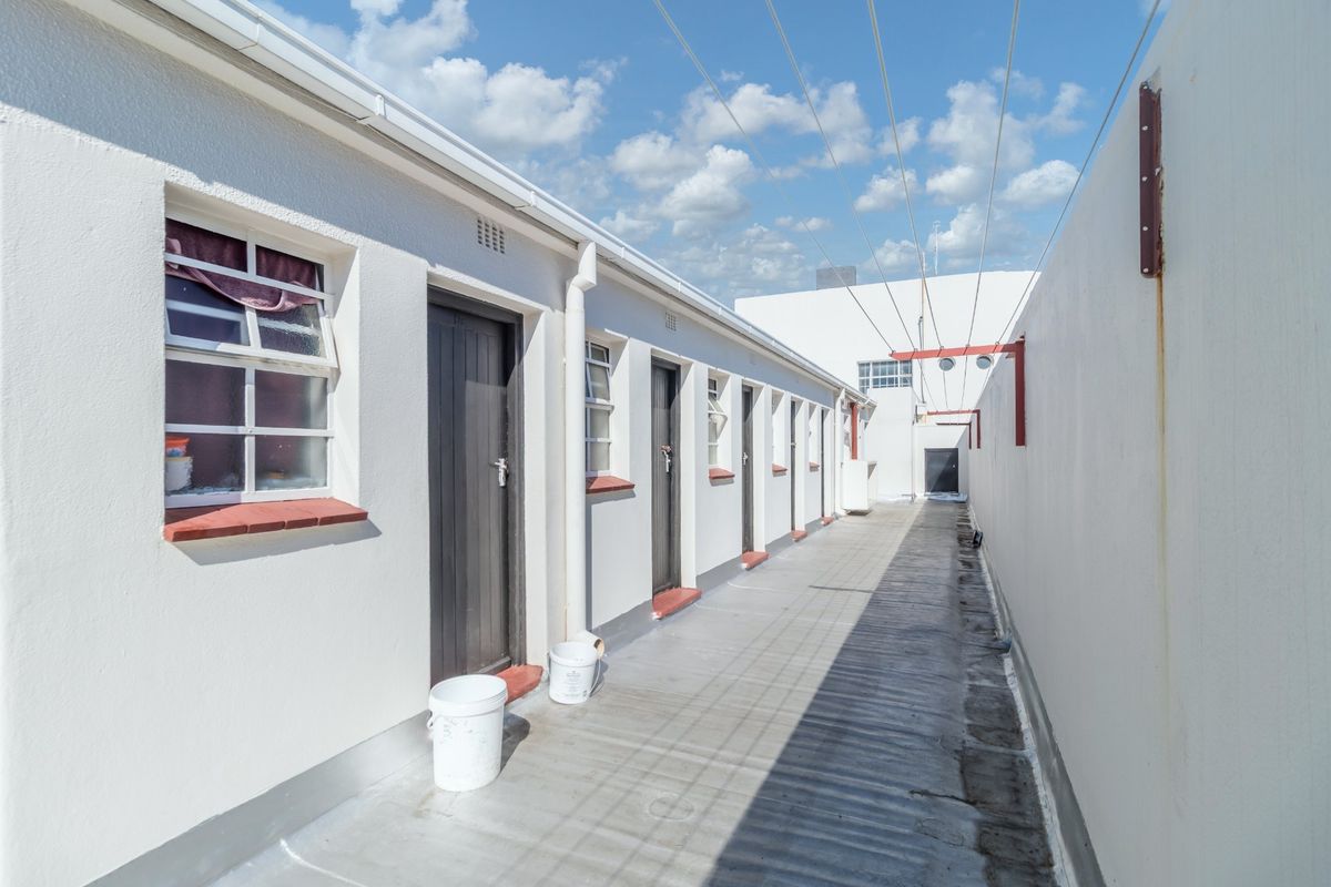 A functional rear exterior walkway featuring multiple access doors, casement windows, and an overhead washing line system.