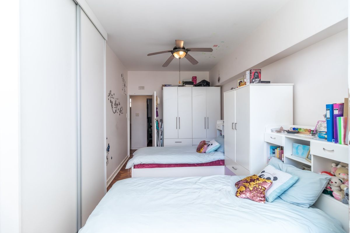 A bedroom featuring built-in sliding door wardrobes, additional built-in cabinetry, and a ceiling fan.