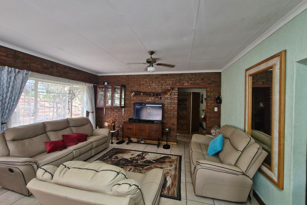 A living room featuring exposed brick feature walls, tiled flooring, and a ceiling fan, providing a rustic and functional living space.