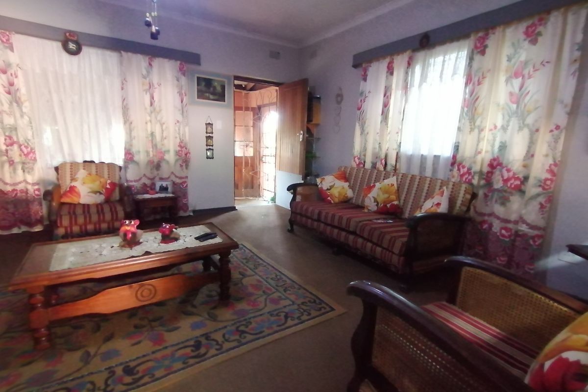 A living room featuring dual windows with curtains and a doorway leading to an exterior entrance.