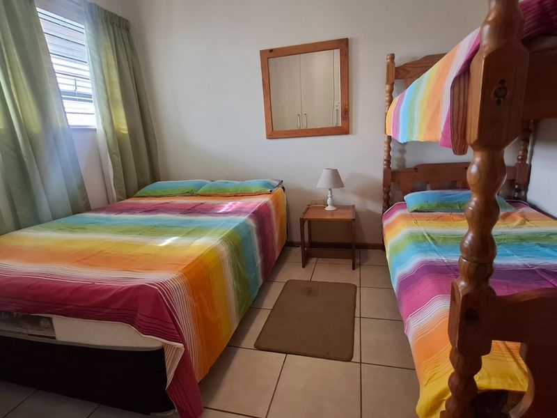 A bedroom featuring tiled flooring and a window with curtains, providing a functional sleeping space.