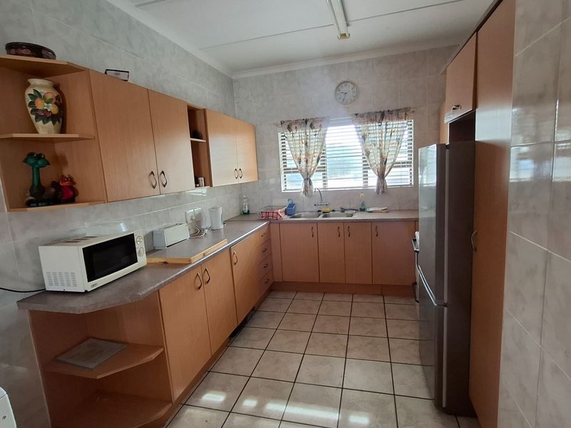 A functional kitchen featuring light wood cabinetry, tiled walls, tiled flooring, and a double basin sink with a window view.
