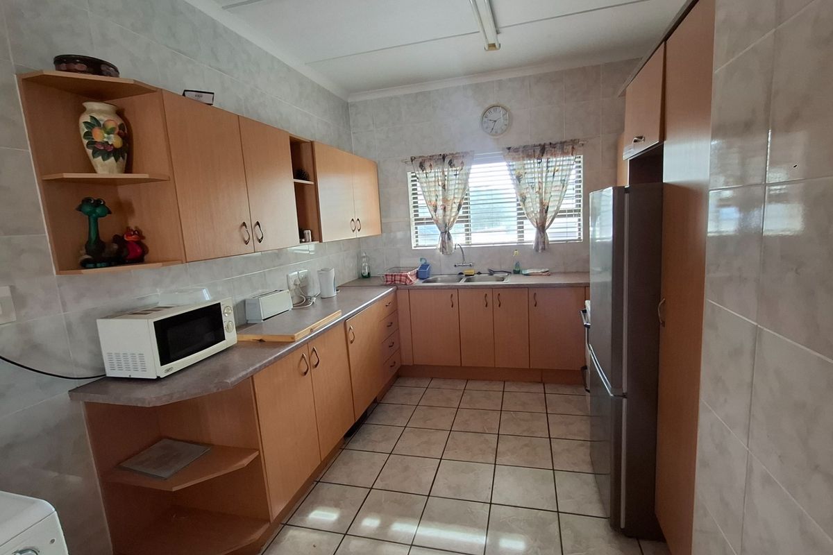A functional kitchen featuring light wood cabinetry, tiled walls, tiled flooring, and a double basin sink with a window view.