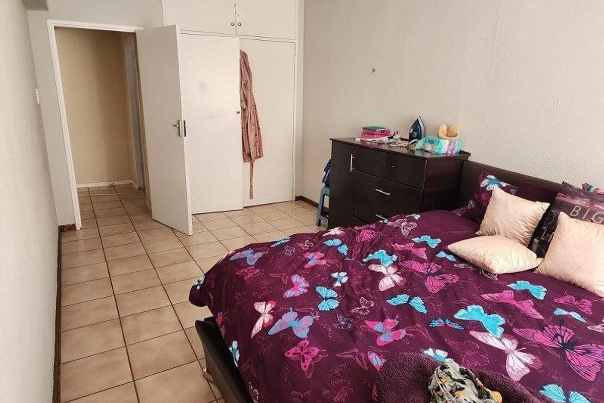 A bedroom featuring tiled flooring and built-in cupboards with overhead storage, providing functional storage space.
