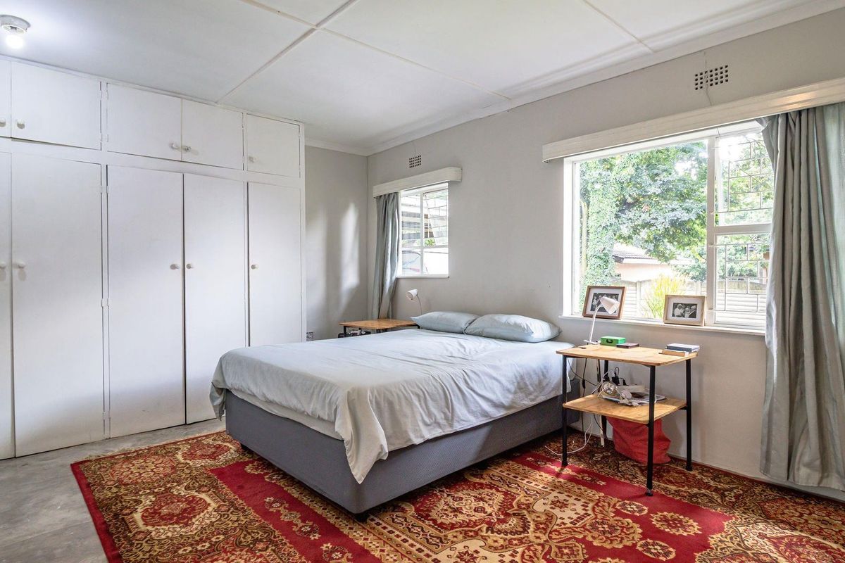 A bedroom featuring built-in floor-to-ceiling cabinetry, large windows providing natural light, and neutral wall finishes.