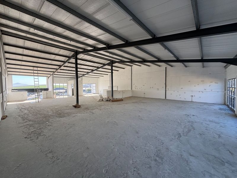 Spacious open-plan industrial unit featuring exposed steel structural framing, insulated roofing, and large windows providing ample natural light.