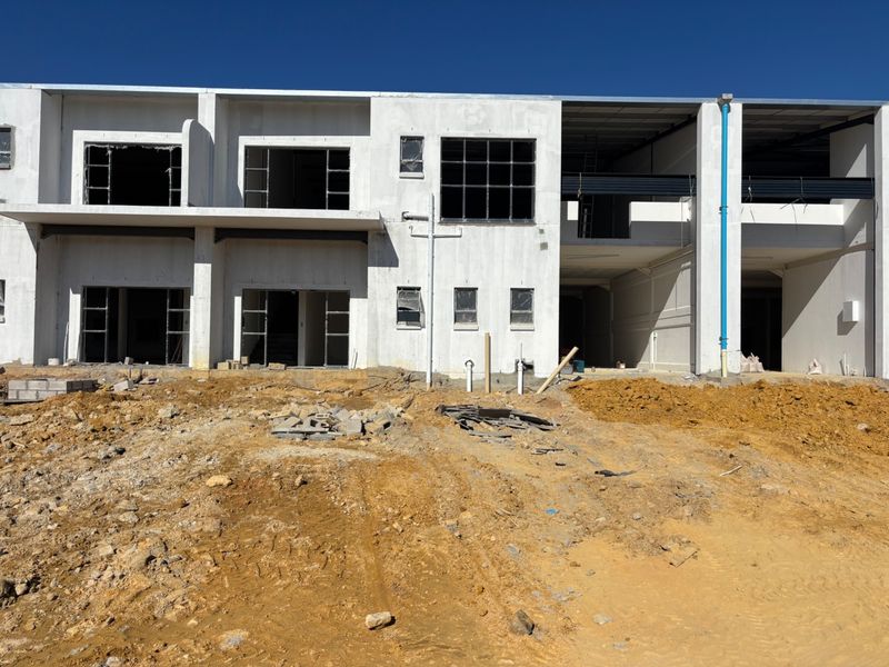 Front elevation of an industrial property under construction, featuring a concrete structure with exposed steel beams and unfinished ground area.