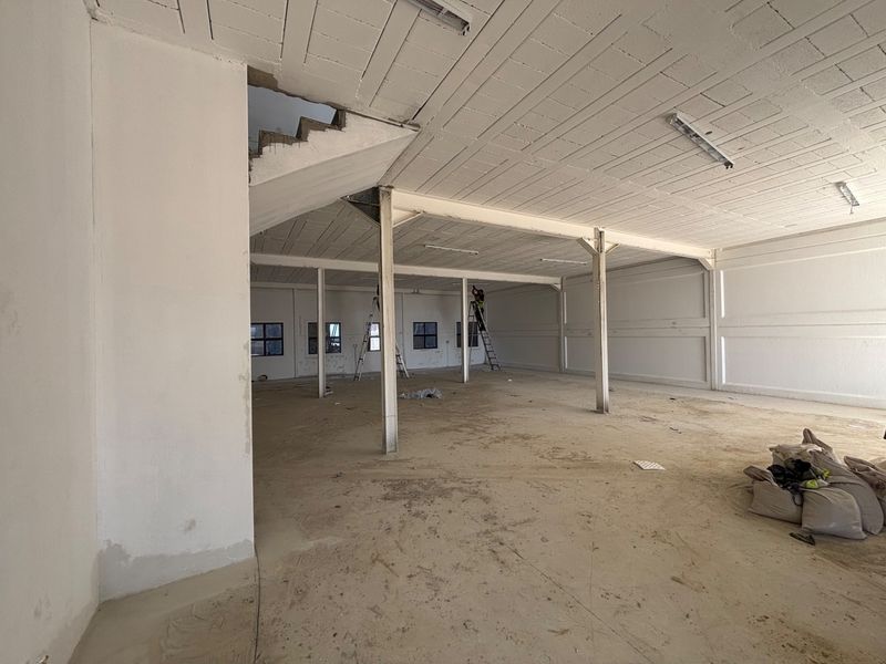 Spacious industrial open-plan area featuring exposed concrete ceilings, steel support columns, and concrete flooring, currently in an unfinished shell condition.