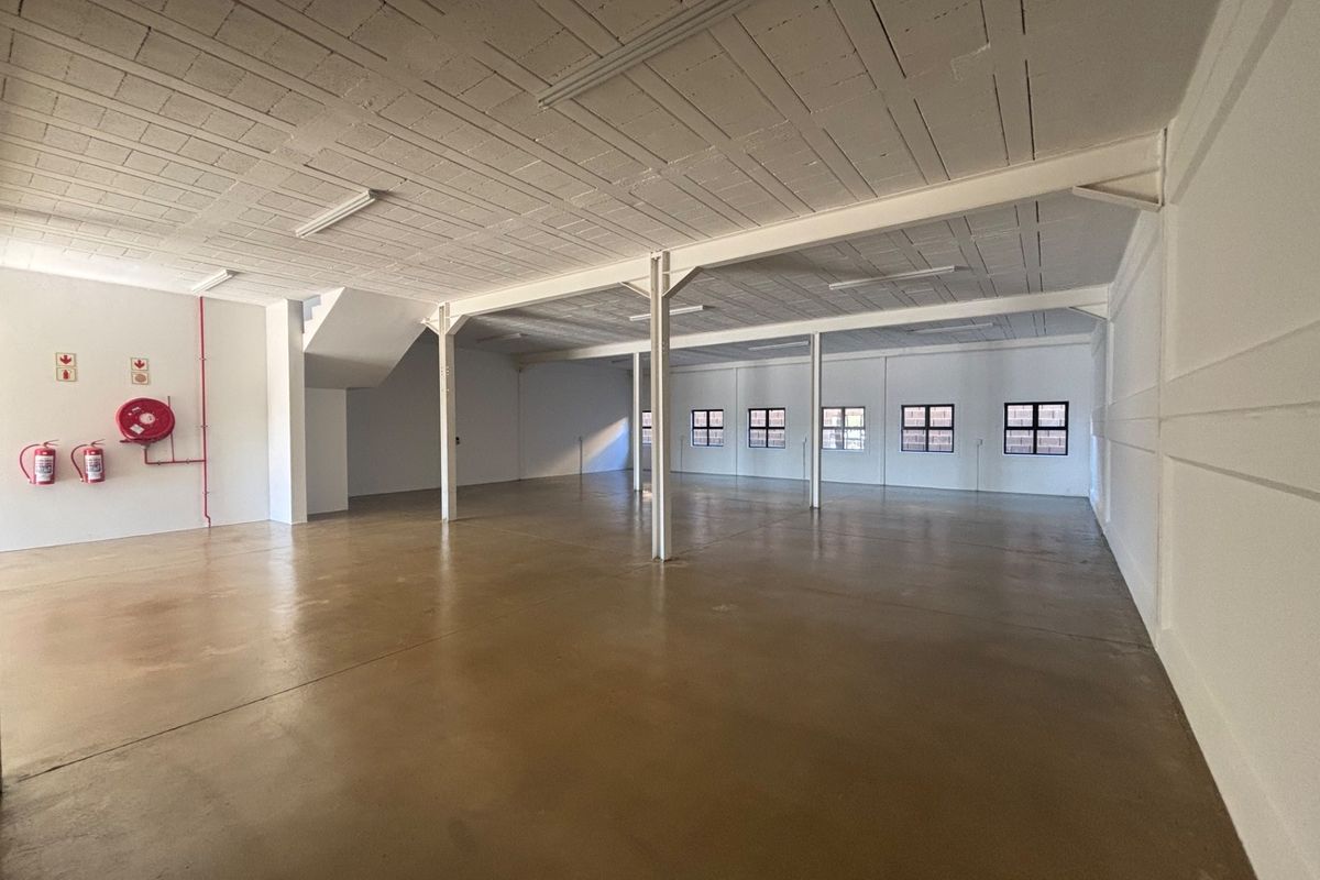 A spacious, open-plan industrial utility area featuring polished concrete floors, exposed beam ceilings, and steel support columns, suitable for various commercial or storage uses.