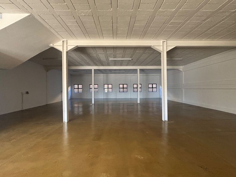 Spacious open-plan industrial unit featuring polished concrete floors, exposed steel support columns, and a high-ceiling design with ample natural light.
