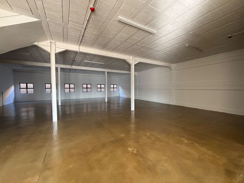 Spacious open-plan industrial unit featuring polished concrete floors, exposed steel support columns, and ample natural light through multiple windows.